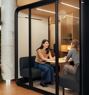 Two people working inside a Framery Four meeting pod